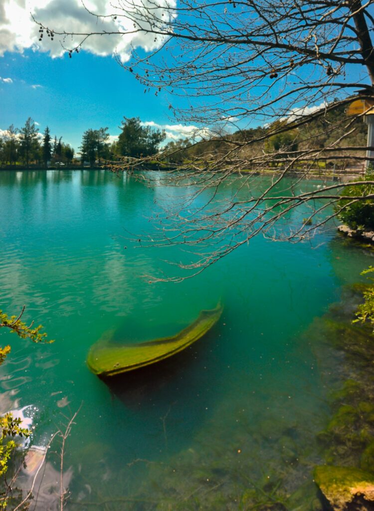 Zaros Lake: Sunken boat at the shores of Zaros Lake, blending with blue-green waters.